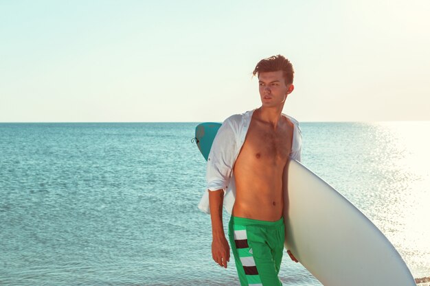 Handsome surfer holding his surfboard