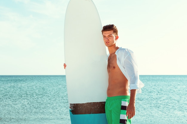 Handsome surfer holding his surfboard