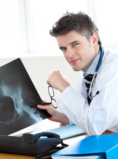 Handsome surgeon analyzing an xray with a female patient