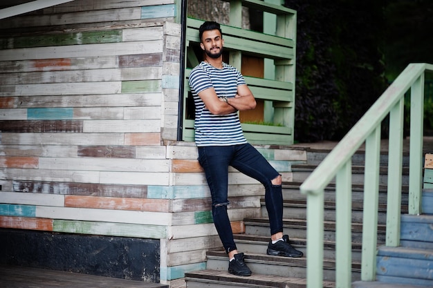 Handsome tall arabian beard man model at stripped shirt posed outdoor Fashionable arab guy