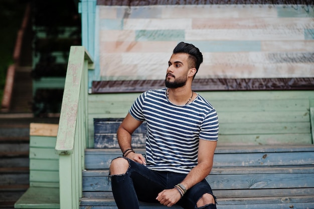 Handsome tall arabian beard man model at stripped shirt posed outdoor Fashionable arab guy