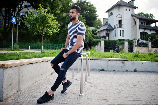 Handsome tall arabian beard man model at stripped shirt posed outdoor Fashionable arab guy