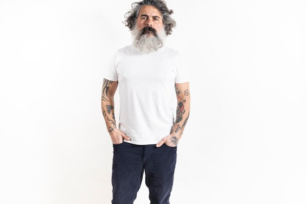 Handsome tattooed bearded man poses in corduroy pants and white premium fine summer tshirt isolated on white background