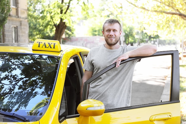 Photo handsome taxi driver near car on station