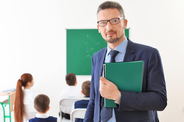 Handsome teacher with notepads in classroom