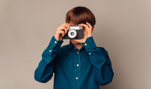 Handsome teen boy in blue shirt is looking through his old vintage camera