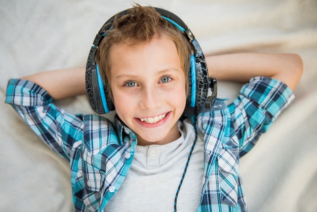 Handsome teen lays and listens to music with headphones