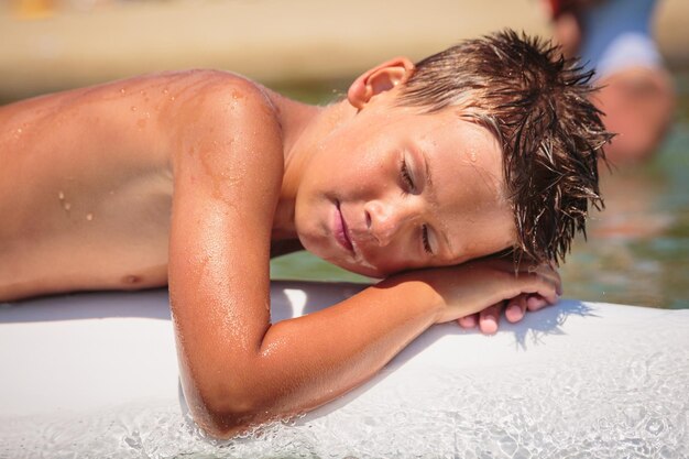 Photo handsome teenage boy having fun floating on a swim board