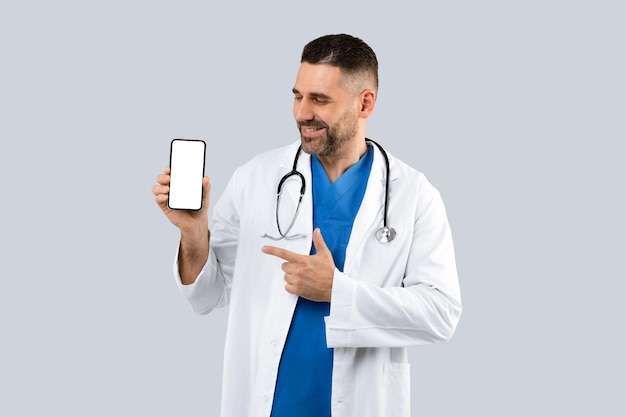 Handsome therapist man showing cellphone with blank screen advertising medical app or website light