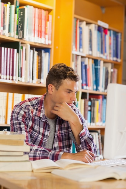 Foto studente premuroso bello che per mezzo del computer