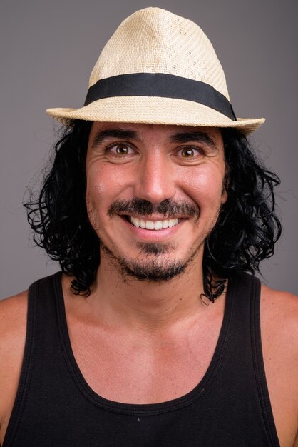 Handsome tourist man wearing hat ready for vacation against gray wall