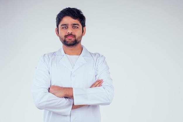 Handsome turkey man surgeon doctor wearing white blazer coat arms crossed on the chest and looking at camera in studio background