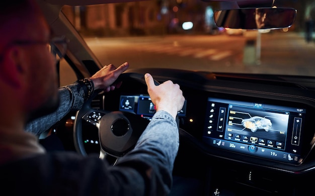 Handsome unshaved man in fashionable clothes riding his automobile