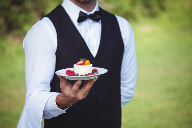 写真 プレートを保持しているハンサムなウェイター