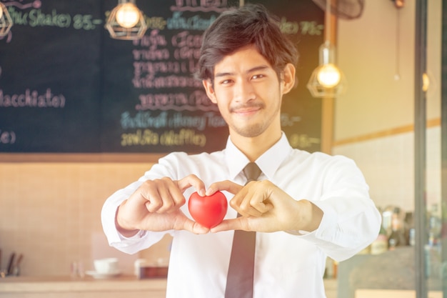 Handsome waiter is serving and holding heart with love on Valentine's Day