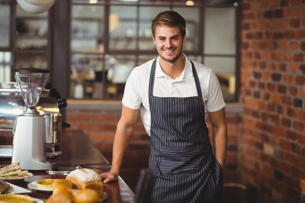 Handsome waiter leaning on a food table