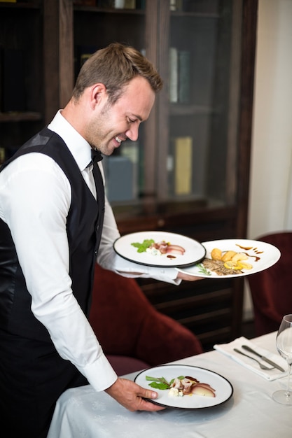 Handsome waiter serving meal