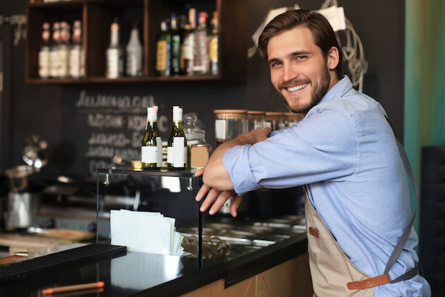 Handsome waiter smiling at camera at the coffee shop.