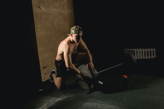 Handsome weightlifter preparing for training with barbell