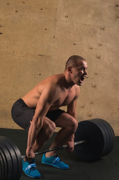 Handsome weightlifter preparing for training with barbell