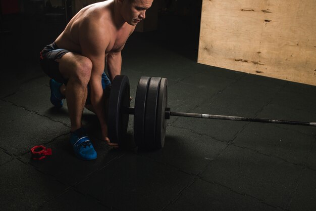 Handsome weightlifter preparing for training with barbell