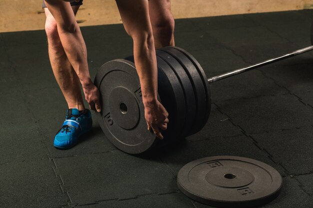 Handsome weightlifter preparing for training with barbell