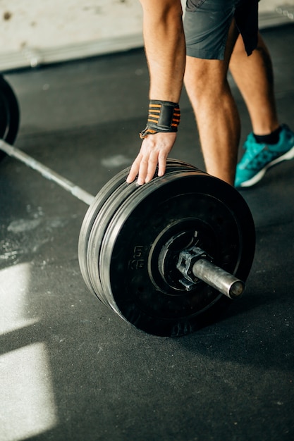 Handsome weightlifter preparing for training with barbell