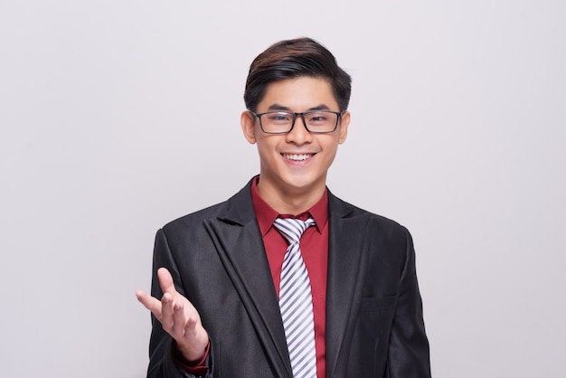 Handsome and well dressed businessman in a suit, tie and vest, standing against a white background smiling towards camera.