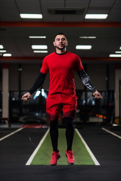 Handsome with big muscles jumping on a rope in the gym