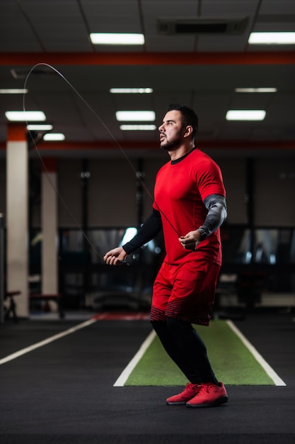 Handsome with big muscles jumping on a rope in the gym