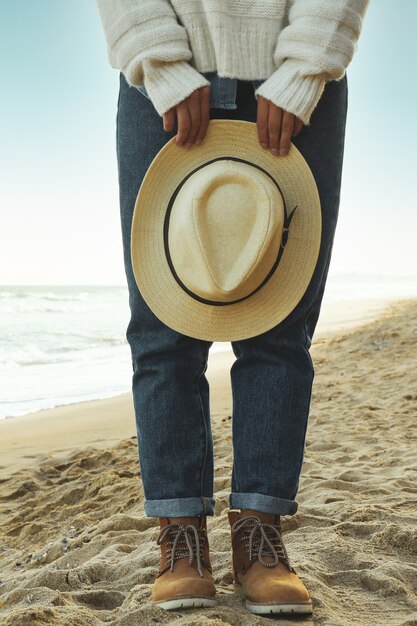 Handsome woman hold hat on sandy beach