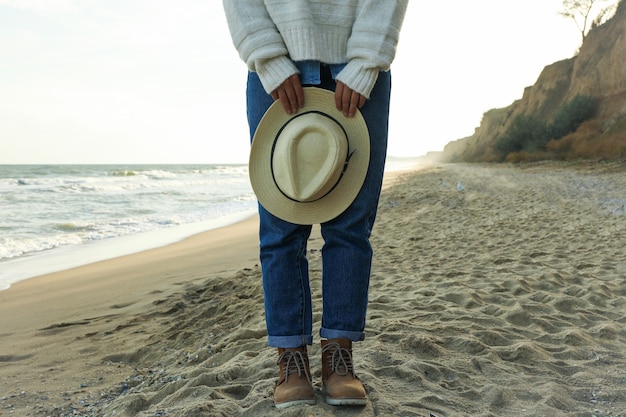 Handsome woman hold hat on sandy beach