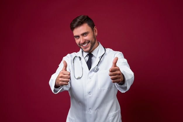 Handsome young adult caucasian doctor on red background showing thumbnails