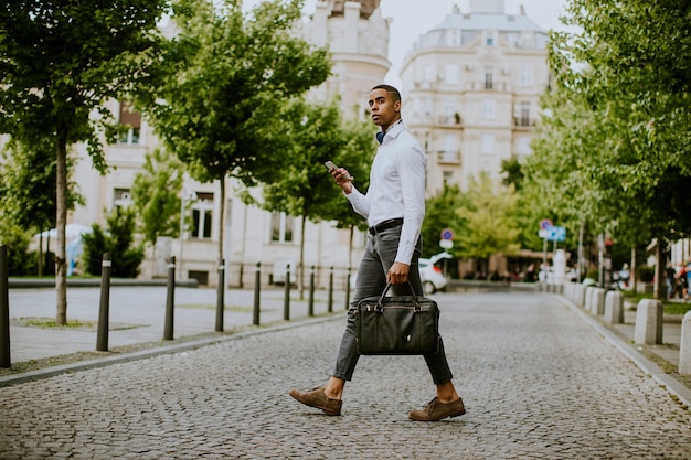 Handsome young African American businessman using a mobile phone on a street