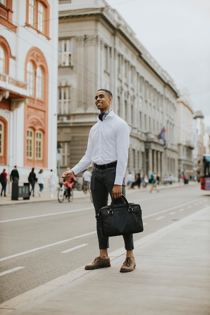 Foto bel giovane uomo d'affari afroamericano in attesa di un taxi su una strada