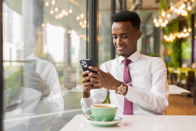 コーヒーショップのレストランでハンサムな若いアフリカのビジネスマン