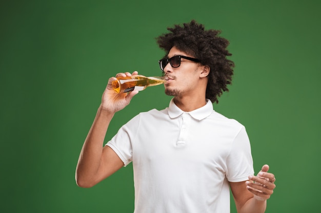 Handsome young african curly man drinking beer.