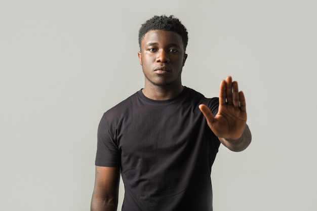 handsome young african man on gray wall with hand gesture