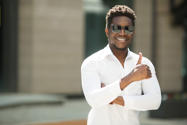 handsome young african man in shirt and sunglasses with hand gesture