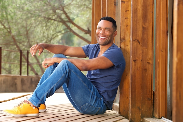 屋外に座って笑っている幸せな若いアフリカの男