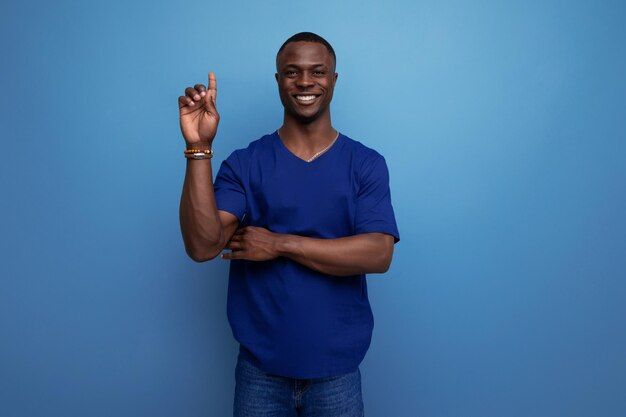 Handsome young american man in blue tshirt shows his hand towards space