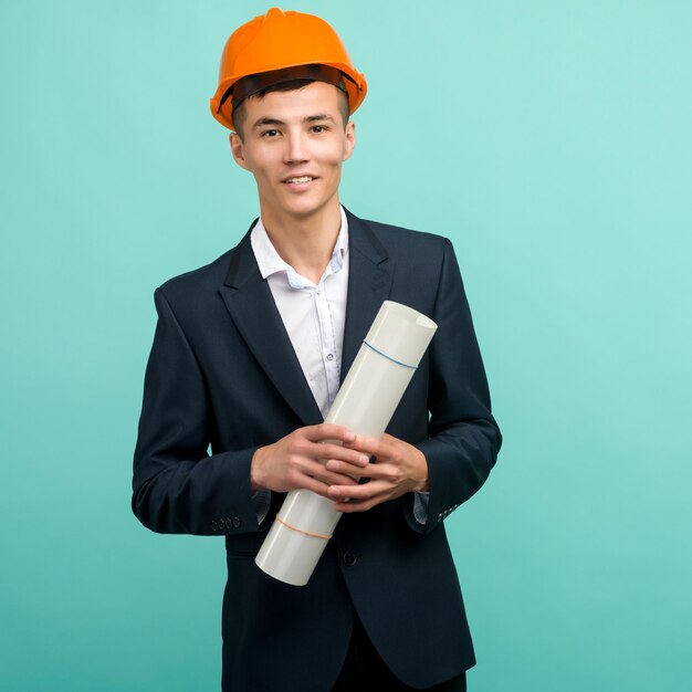 Handsome young asian man architect holding a drawing on blue background