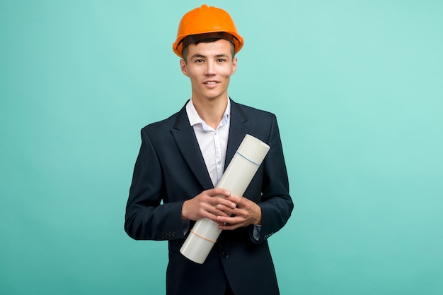 Handsome young asian man architect holding a drawing on blue background