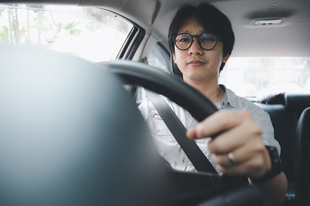 차를 운전하는 동안 안전 벨트를 사용하는 잘 생긴 젊은 아시아 남자