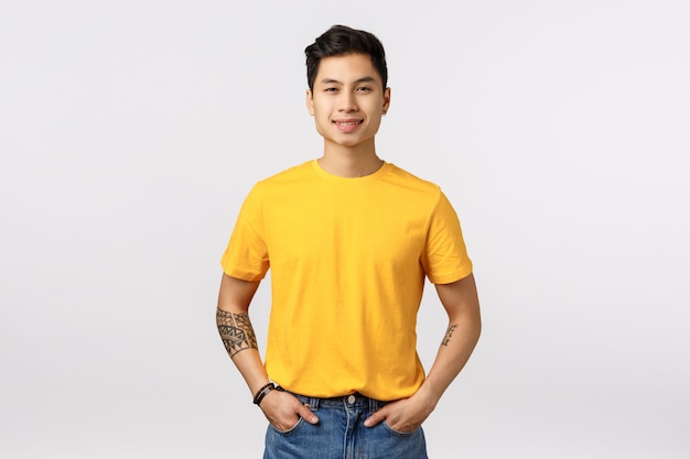 黄色のtシャツのポーズでハンサムな若いアジア人