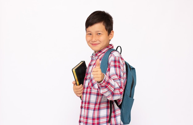 Handsome young asian schoolboy with backpack smiling over white background