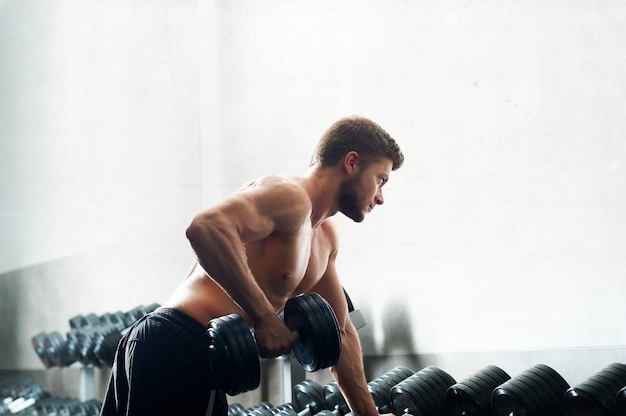 Handsome young athlete working out at the gym 