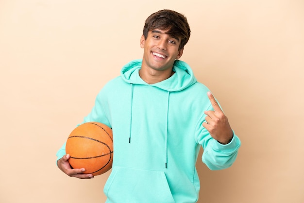Handsome young basketball player man isolated on ocher background doing coming gesture