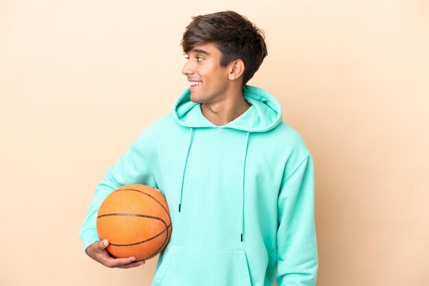 Handsome young basketball player man isolated on ocher background looking side