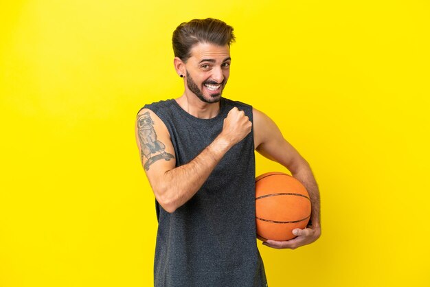 Handsome young basketball player man isolated on yellow background celebrating a victory